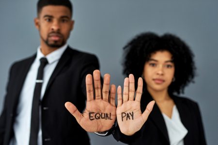 Shot of a businessman and businesswoman advocating for equal pay against a grey studio background